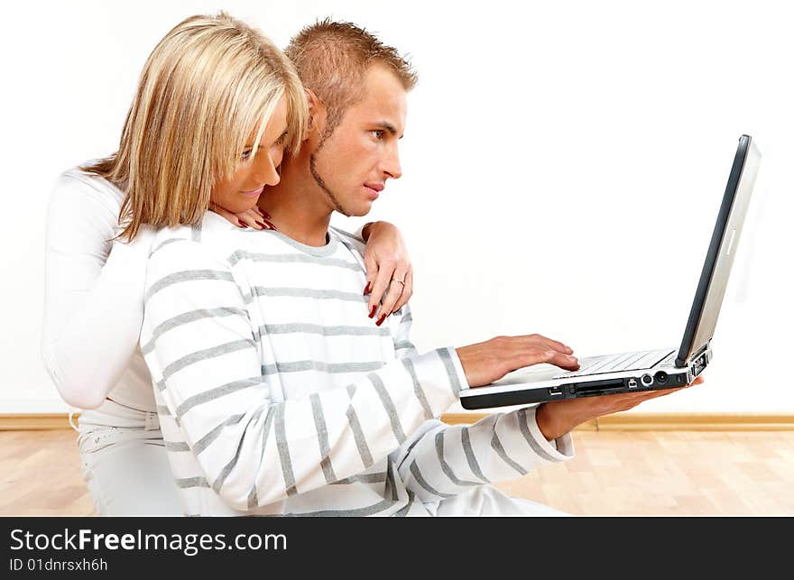 Portrait of a happy couple sitting on the floor with laptop. Portrait of a happy couple sitting on the floor with laptop