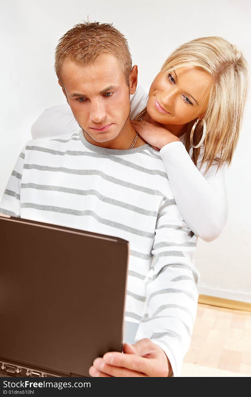 Portrait of a happy couple sitting on the floor with laptop. Portrait of a happy couple sitting on the floor with laptop