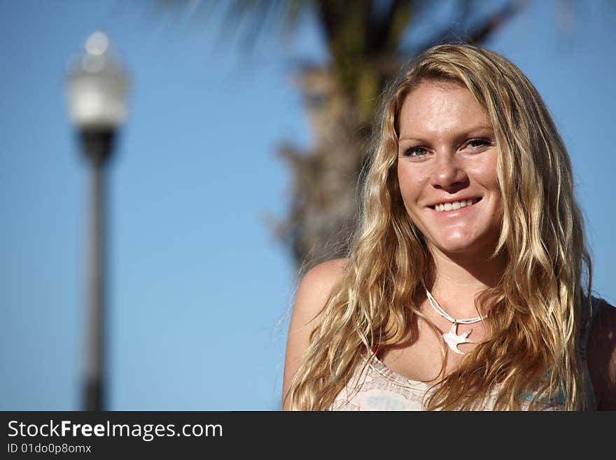 Woman smiling with a lamp post and a tree on the blue background