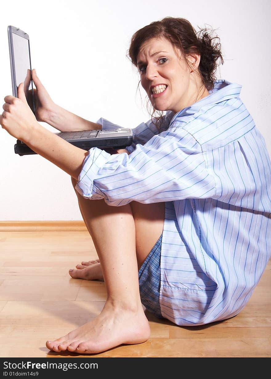 A young woman at home with her laptop sitting on the floor in her new appartment. She seems to be very frustrated. A young woman at home with her laptop sitting on the floor in her new appartment. She seems to be very frustrated.