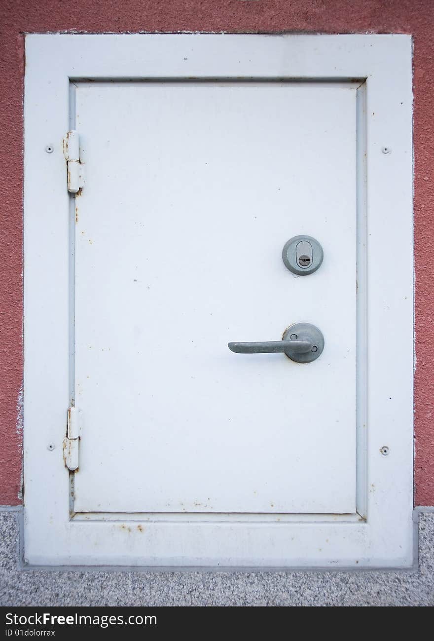 Very small white metal door with lock and handle. Very small white metal door with lock and handle.