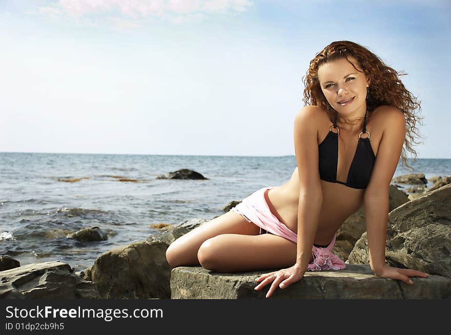 girl sits on a stone on a sea beach