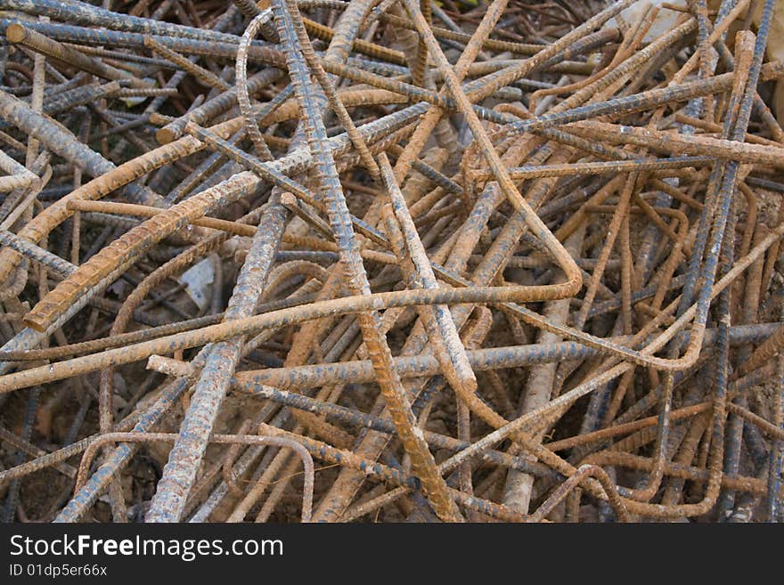 A chaotic pile of bent and rusty scrap rebar (steel reinforcement bar) at a construction site. Useful as a background, with great texture. A chaotic pile of bent and rusty scrap rebar (steel reinforcement bar) at a construction site. Useful as a background, with great texture.