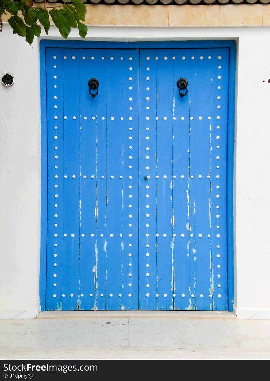 Traditional blue wooden house door with knockers in Monastir Medina, Tunisia. Traditional blue wooden house door with knockers in Monastir Medina, Tunisia.