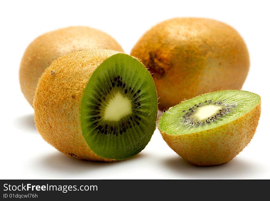 Three kiwi isolated on a white background. At the forefront of a kiwi cut into two parts. Background blurred. Three kiwi isolated on a white background. At the forefront of a kiwi cut into two parts. Background blurred.