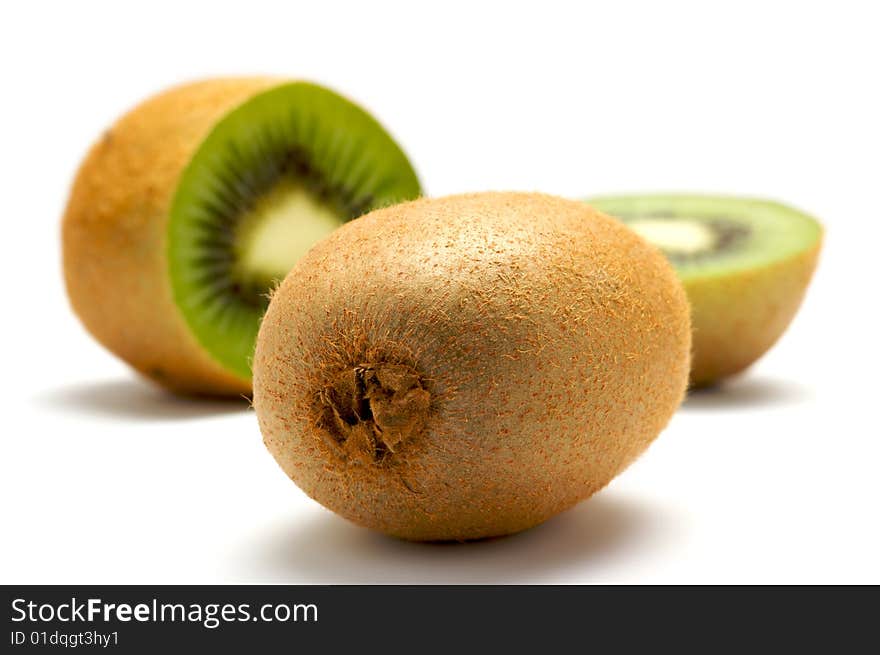 Two kiwi isolated on a white background. In the background kiwi cut into two parts. Background blurred. Two kiwi isolated on a white background. In the background kiwi cut into two parts. Background blurred.