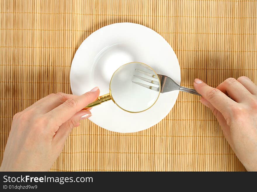 Examining of meal on a plate through a magnifier. Examining of meal on a plate through a magnifier