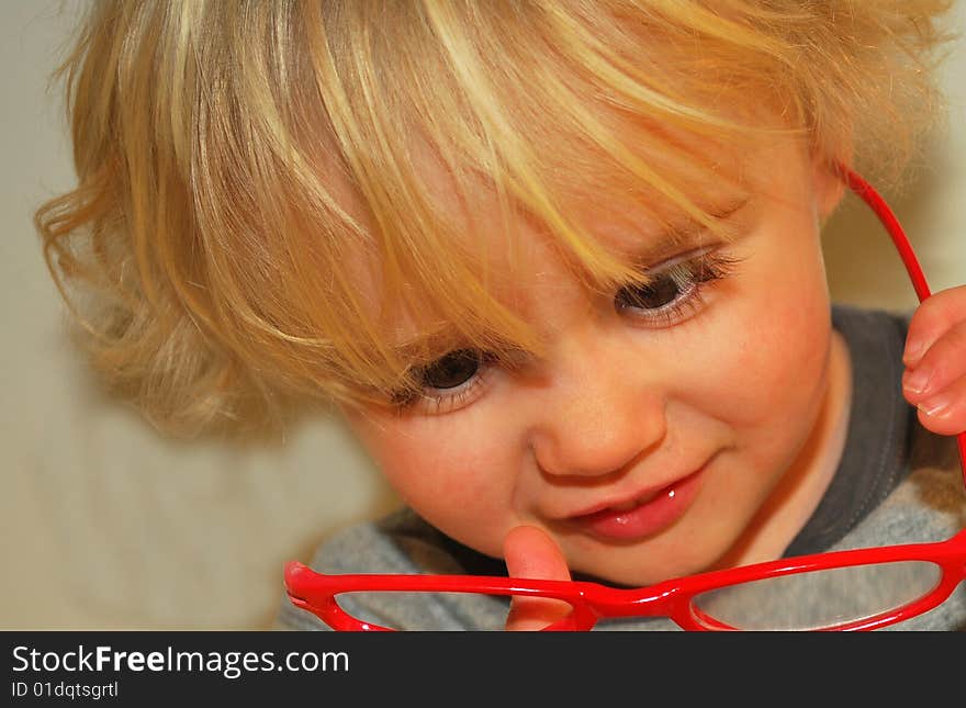 Toddler checking out red eyeglasses