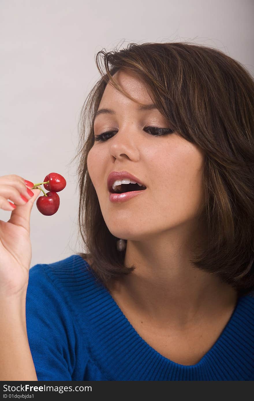 A beautiful young Asian-American girl eating red cherries