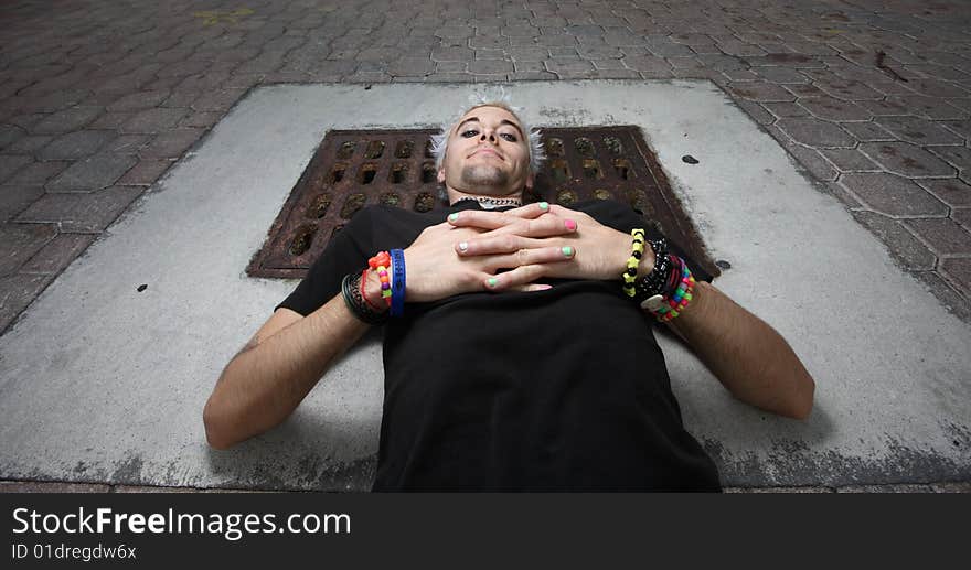 Man laying on a sewer cover. Man laying on a sewer cover