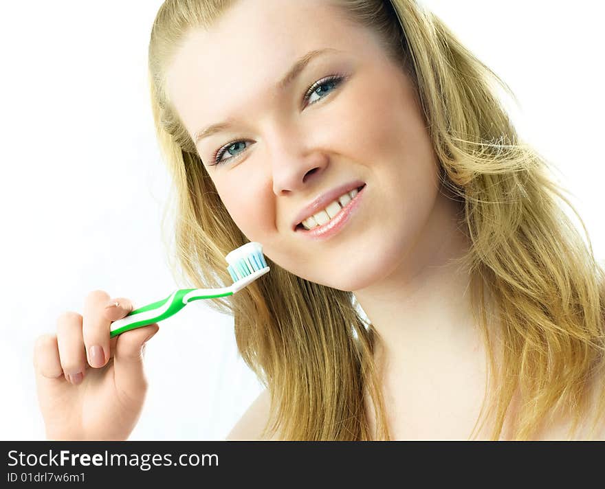 Portrait of a happy young blond woman brushing her teeth