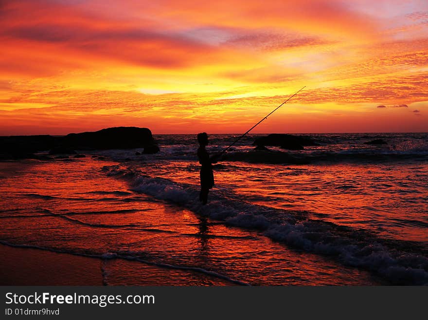 Man with fishing rod on coastline at sunset time. Man with fishing rod on coastline at sunset time