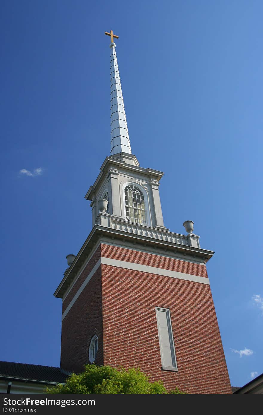 A traditional-style church steeple topped by a cross rises into a brilliant blue sky, with a few nice-day white clouds.

Focus is on the steeple & cross.
Includes copy space.
Please use respectfully.