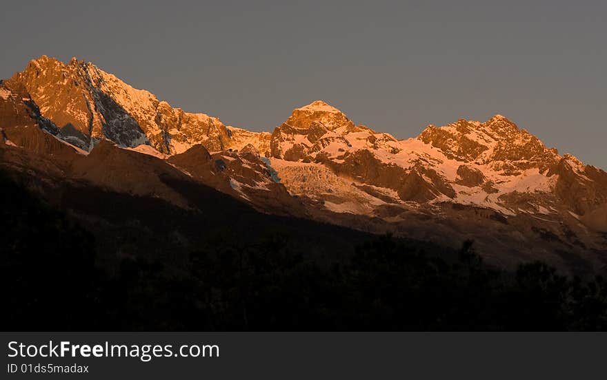 Locating between 10004'-10016'east longitude and 2703'-2740' north latitude, Jade Dragon Snow Mountain (Yulong Mountain) is the southernmost glacier in the Northern Hemisphere. Consisting of 13 peaks, among which Shanzidou is the highest one with an altitude of 5,600 meters (18,360 feet), Jade Dragon Snow Mountain stretches a length of 35 kilometers (22 miles) and a width of 20 kilometers (13 miles). Looking from Lijiang Old Town in the south which is 15 kilometers (nine miles) away, the snow-covered and fog-enlaced mountain resembles a jade dragon lying in the clouds, hence, the name Jade Dragon Snow Mountain