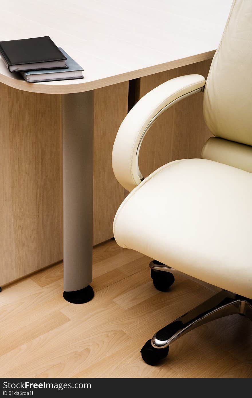 White leather armchair and books laying on a table