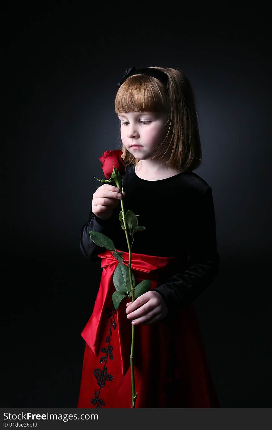 Young girl smelling a long stemmed rose