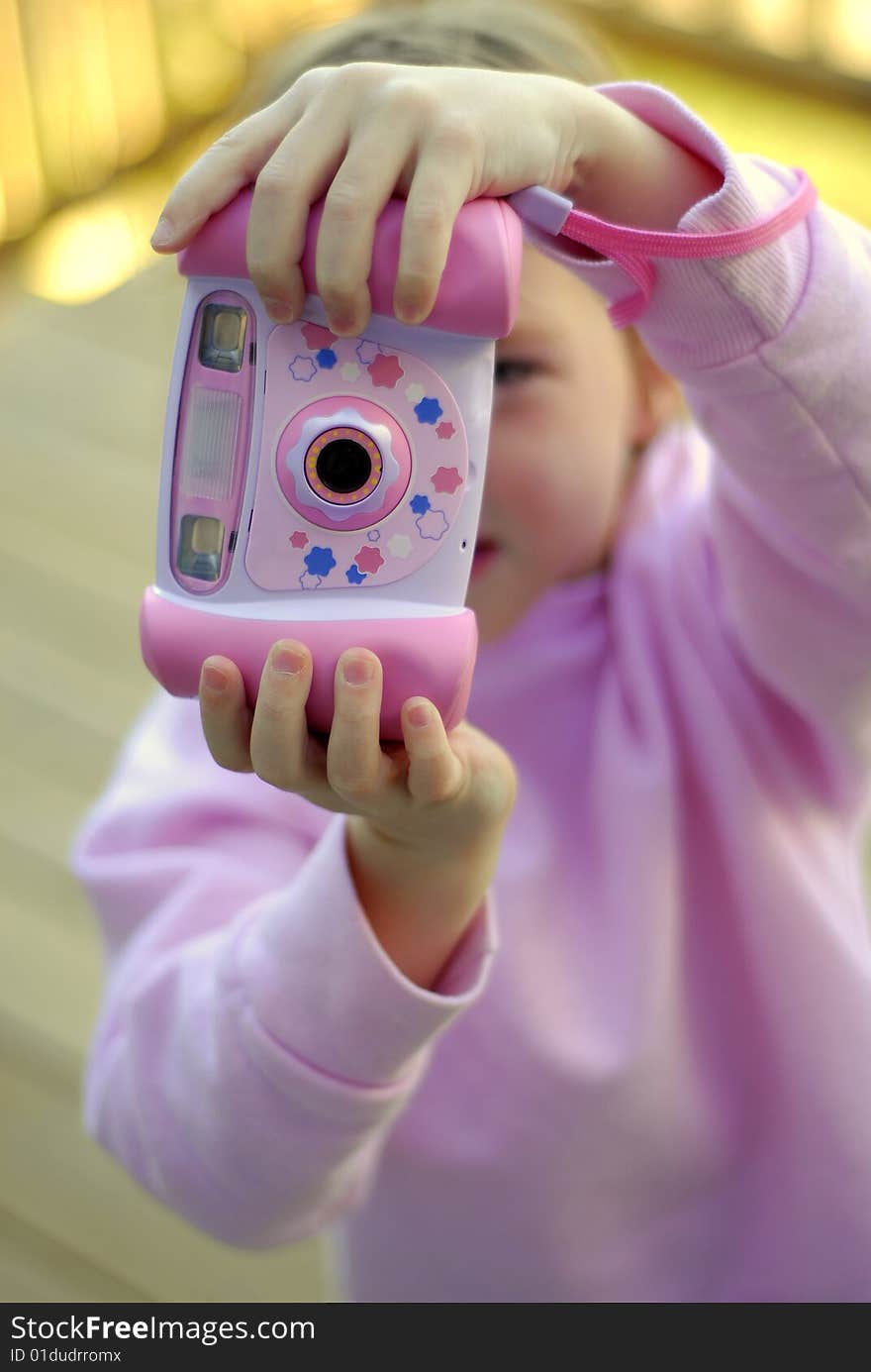 Little girl holding a pink camera taking pictures. Little girl holding a pink camera taking pictures