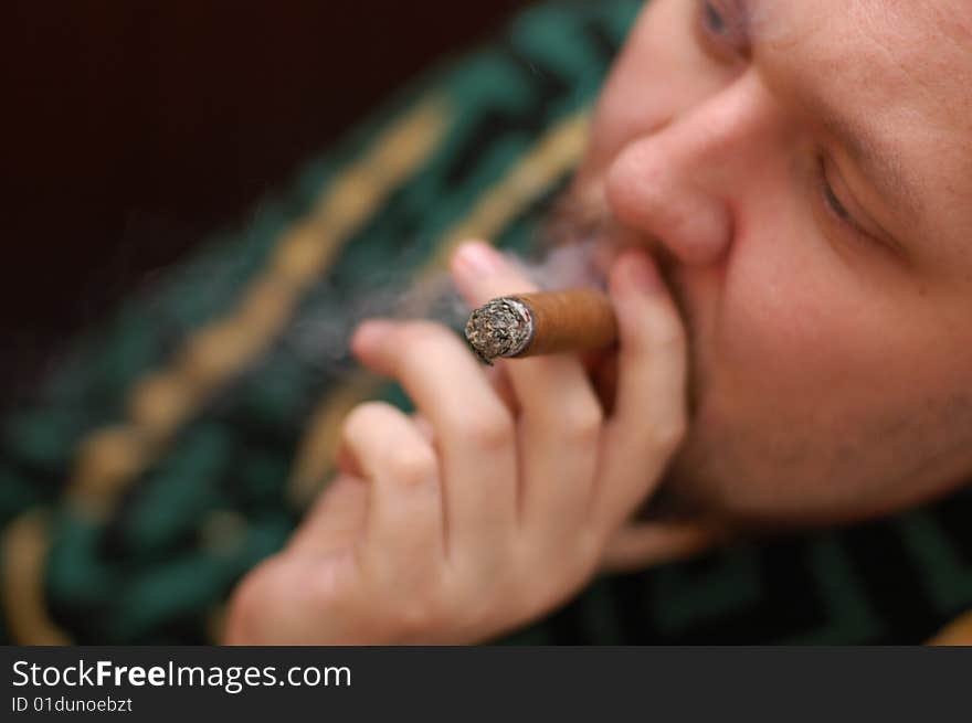 Man in dressing gown smokes cigar. Focus on cigar