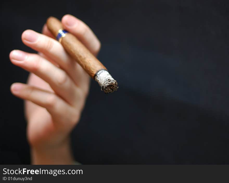 Hand with cigar at black background