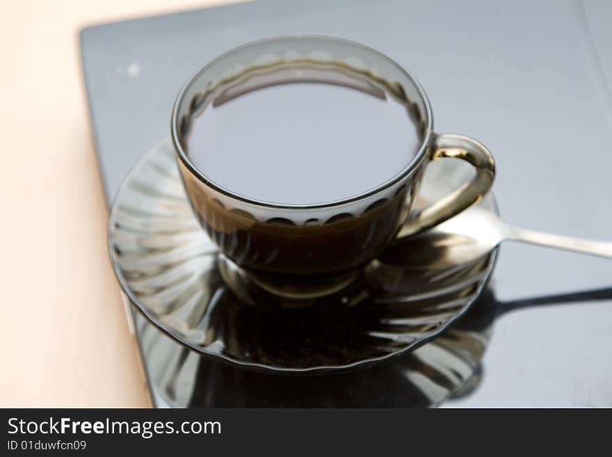 Espresso coffee cup with steel spoon on the laptop