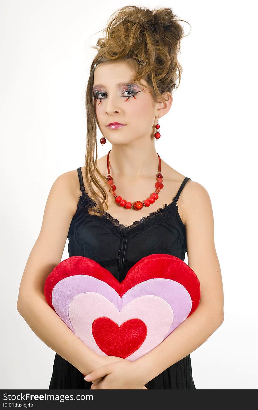 Fashion girl with red necklace and black top holding a valentine's day heart shaped pillow in her hand. Fashion girl with red necklace and black top holding a valentine's day heart shaped pillow in her hand