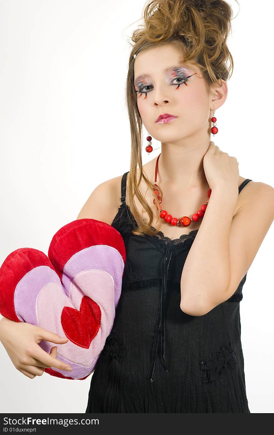 Fashion girl with red necklace and black top holding a valentine's day heart shaped pillow in her hand. Fashion girl with red necklace and black top holding a valentine's day heart shaped pillow in her hand