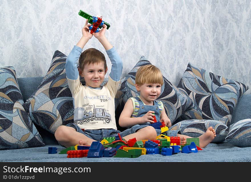 Two boys sitting on a sofa play toys. Two boys sitting on a sofa play toys