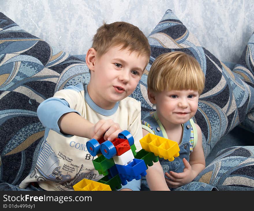 Two boys sitting on a sofa play toys. Two boys sitting on a sofa play toys