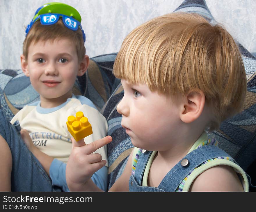 Two boys sitting on a sofa play toys. Two boys sitting on a sofa play toys