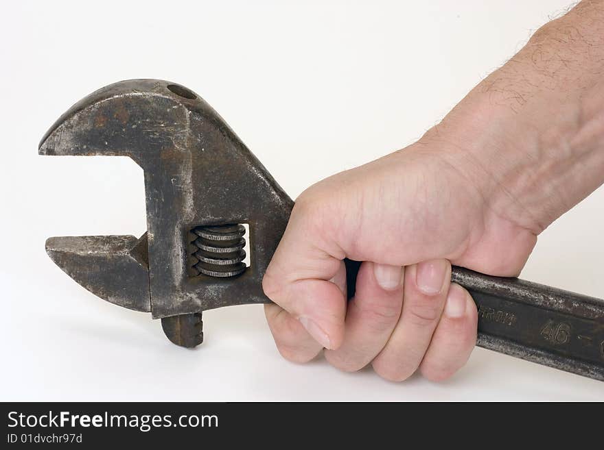 Old spanner in a hand on a light background. Old spanner in a hand on a light background.