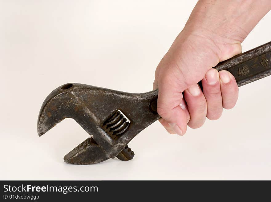 Old spanner in a hand on a light background. Old spanner in a hand on a light background.