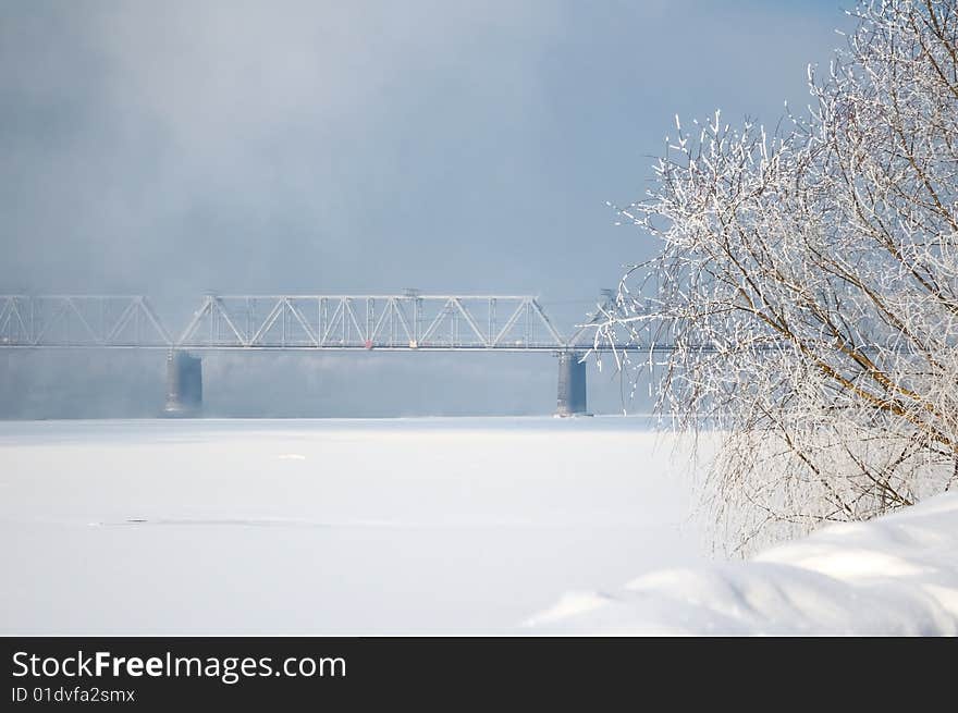 Winter view on the riverside with railway bridge