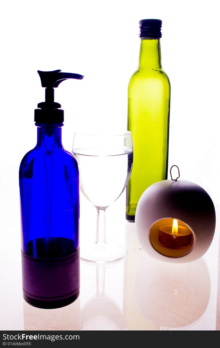 Brightly colored bottles and a lit candle. Brightly colored bottles and a lit candle