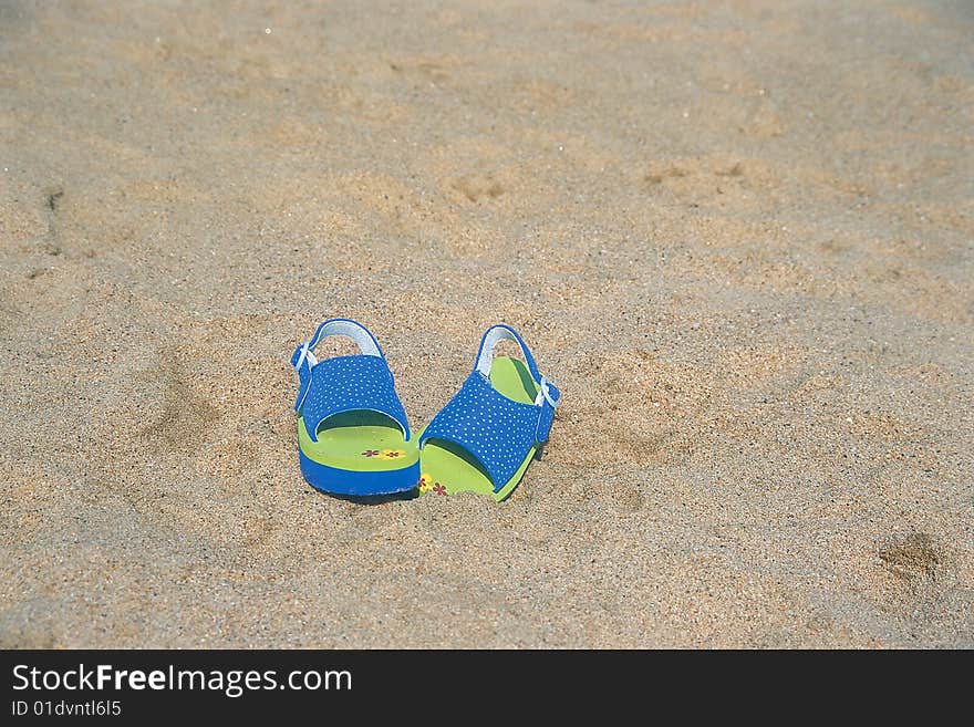 A pair of children sandals laying lost on the beach. A pair of children sandals laying lost on the beach