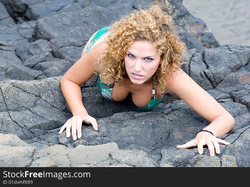 A girl stands by the rocks on the beach. A girl stands by the rocks on the beach