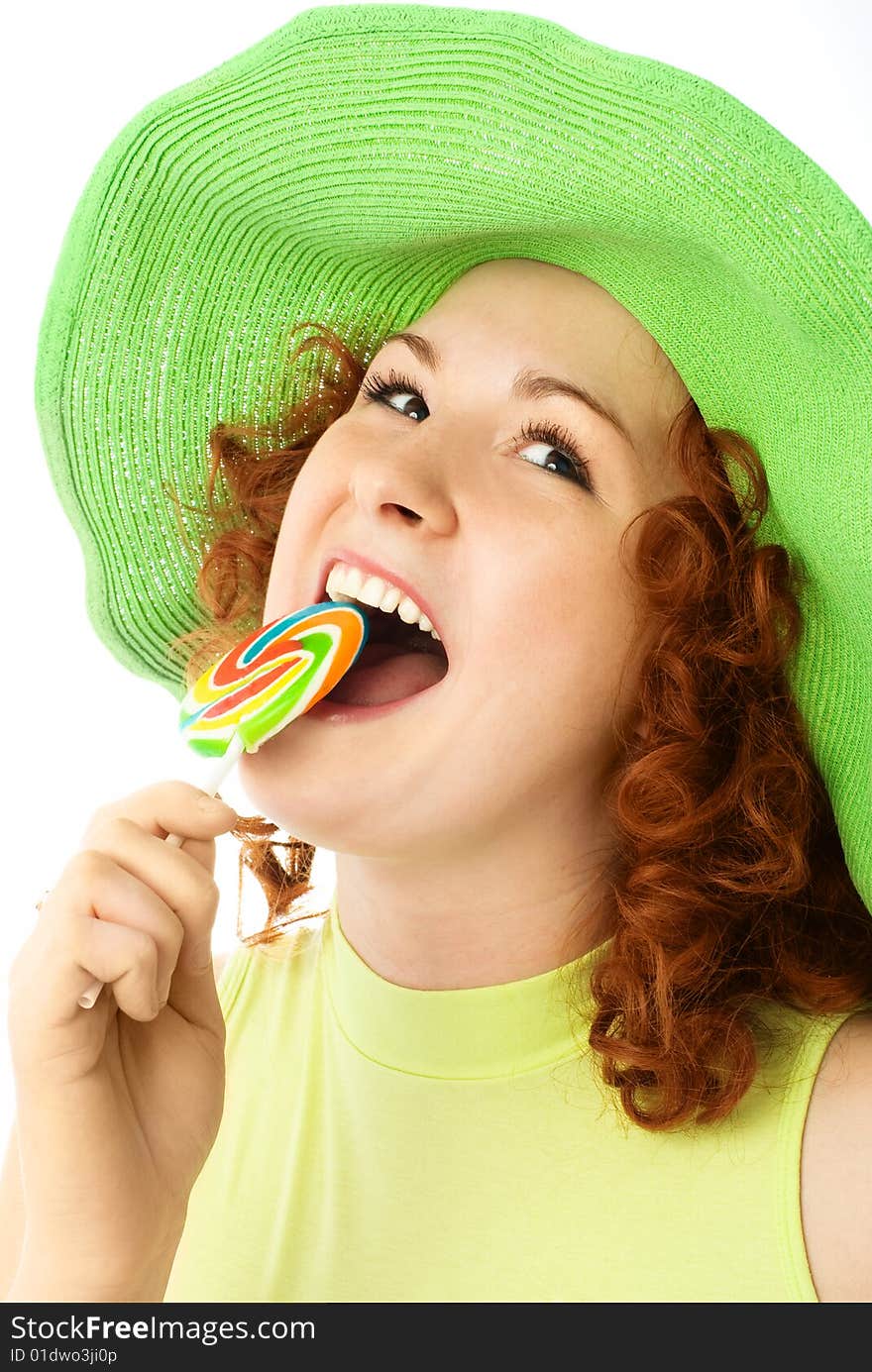 Happy young woman with ginger hair eating a colorful candy. Happy young woman with ginger hair eating a colorful candy