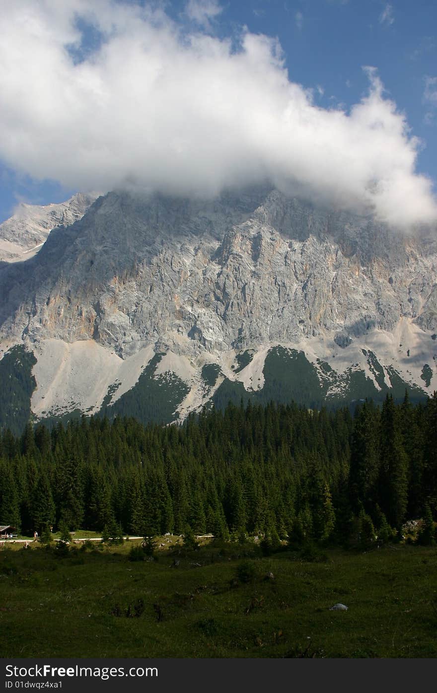 Clouds on mountains behind Alpine forest