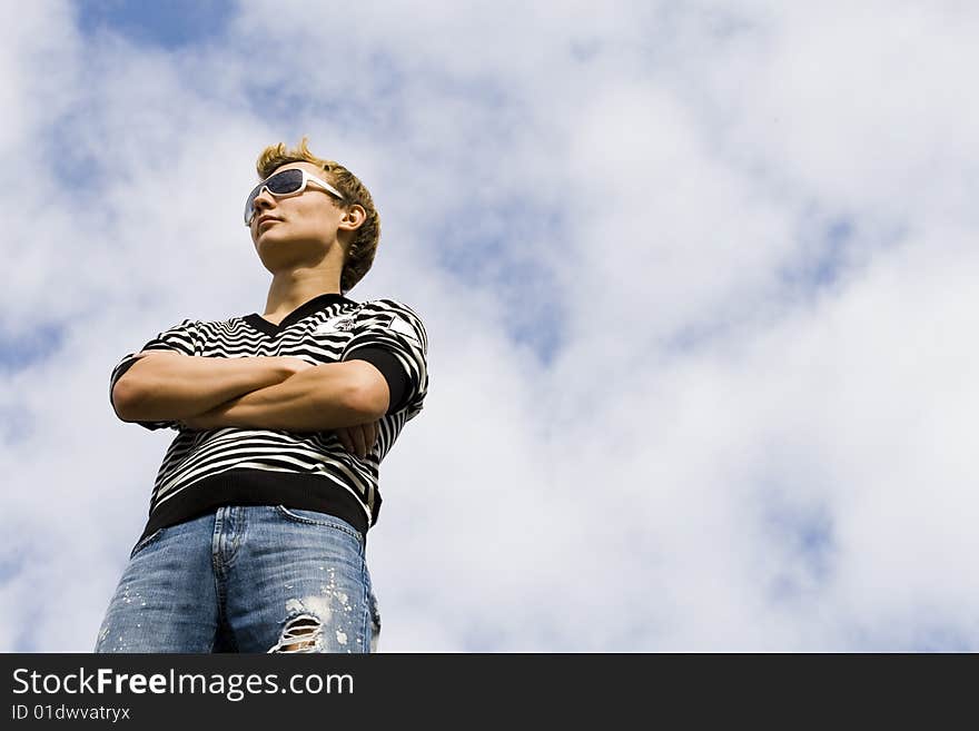 Young beautiful man model standing under the cloud