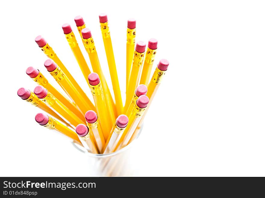 Yellow pencils with a rubber on the end in a glass