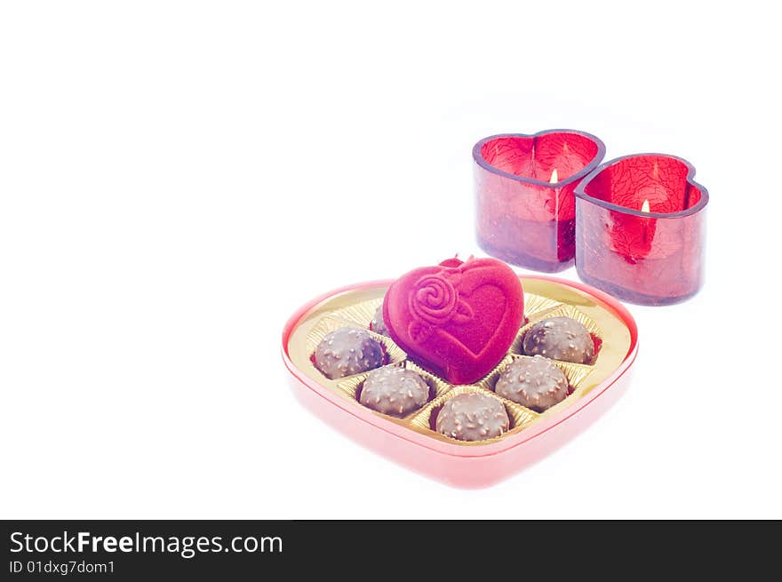 Valentine's day setup with a heart shape chocolate box with jewerly box and two red candle in the middle