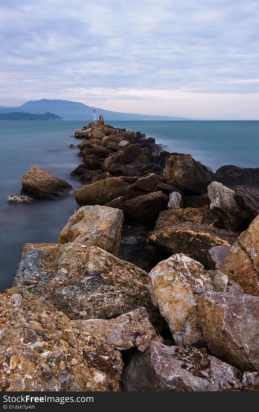 Picture of a rocky formation extending into the sea. Room for text on top. Picture of a rocky formation extending into the sea. Room for text on top