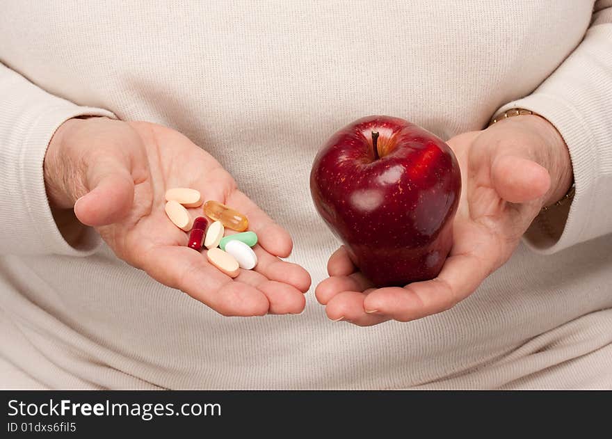 Senior Woman Holding Pills and Apple in her Palms.