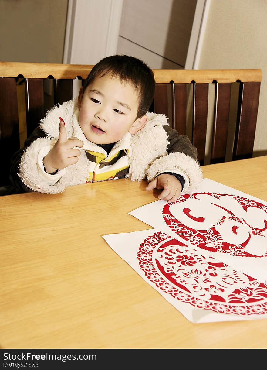 A picture of a chinese little boy playing with paper-cuts curiously. A picture of a chinese little boy playing with paper-cuts curiously