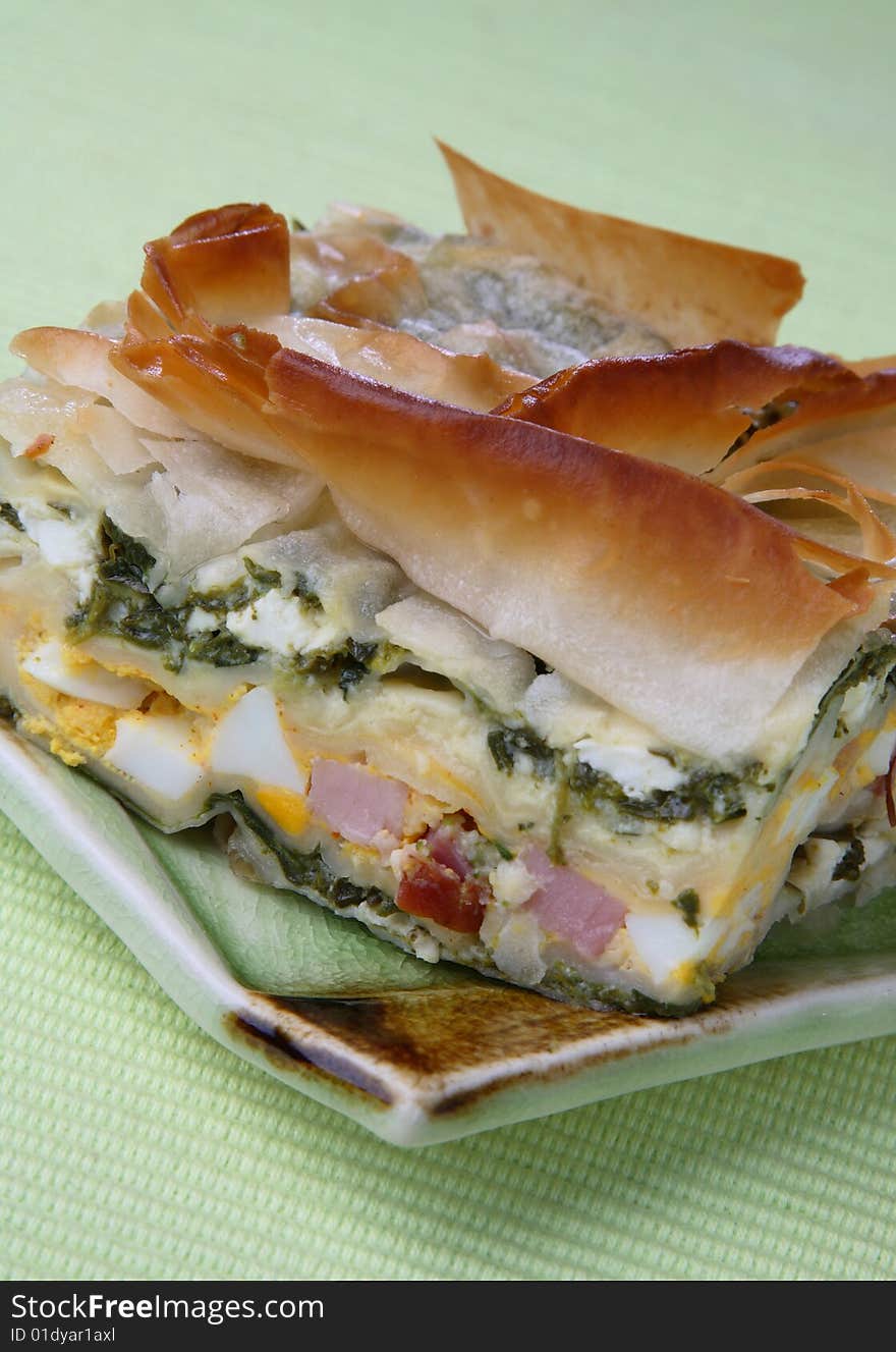 Baked pie with ham, spinach and boiled eggs on plate