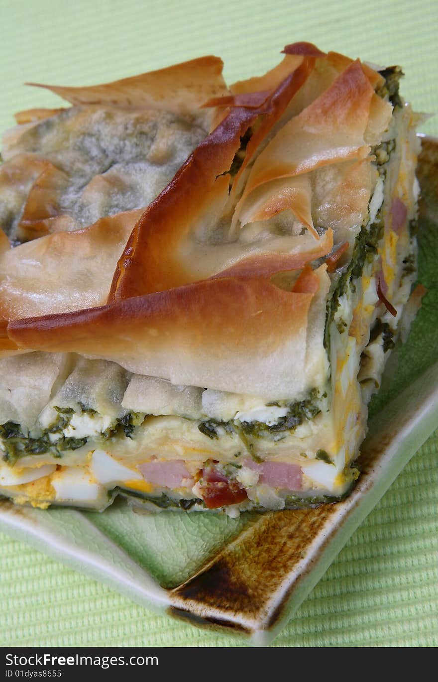 Baked pie with ham, spinach and boiled eggs on plate