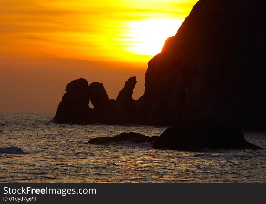 Orange sunset over water with rocks shape