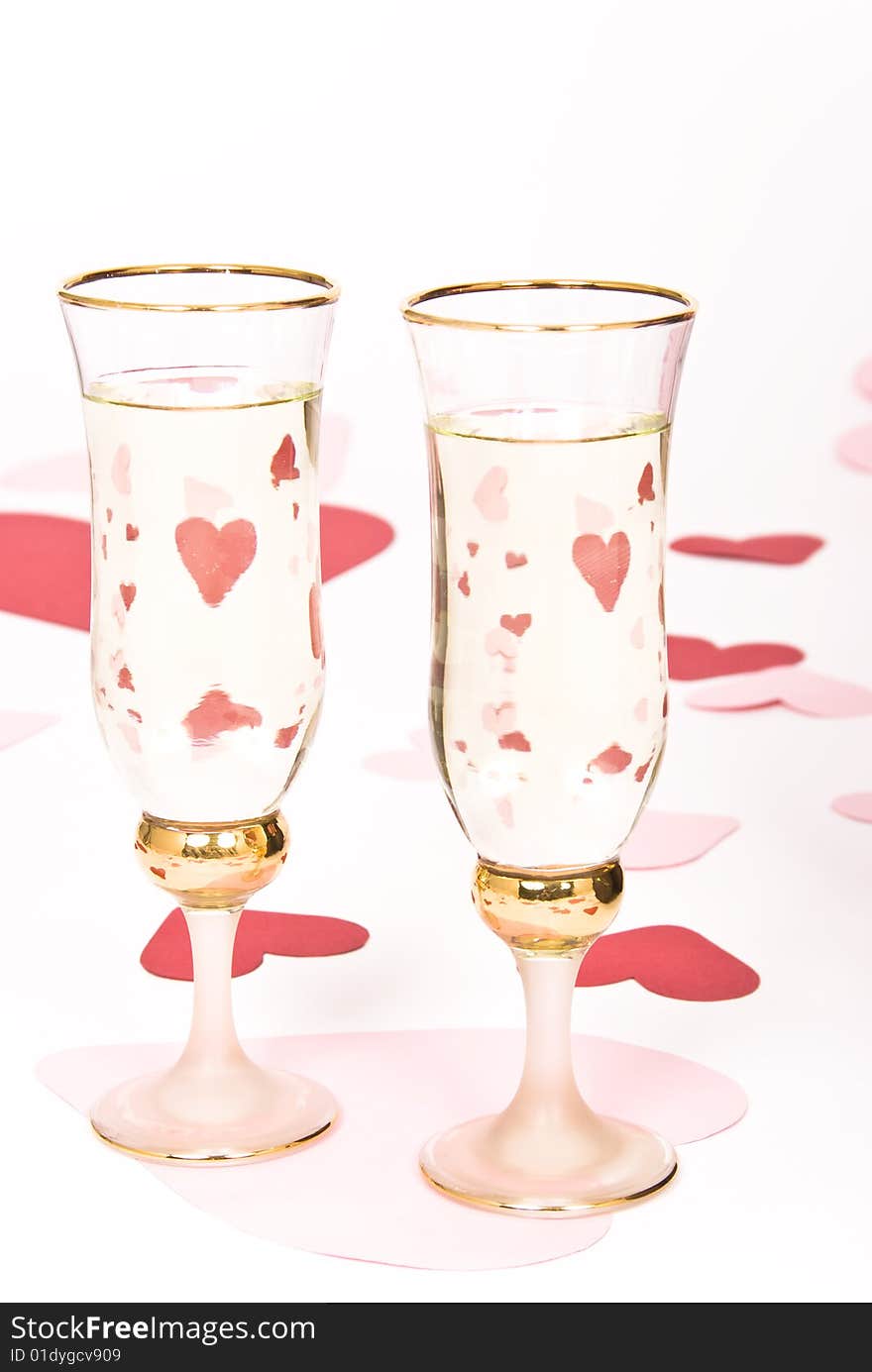 Two glasses  of white wine on white heart covered background