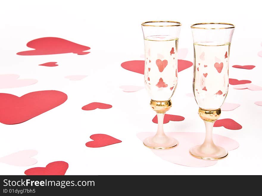 Two glasses  of white wine on white heart covered background