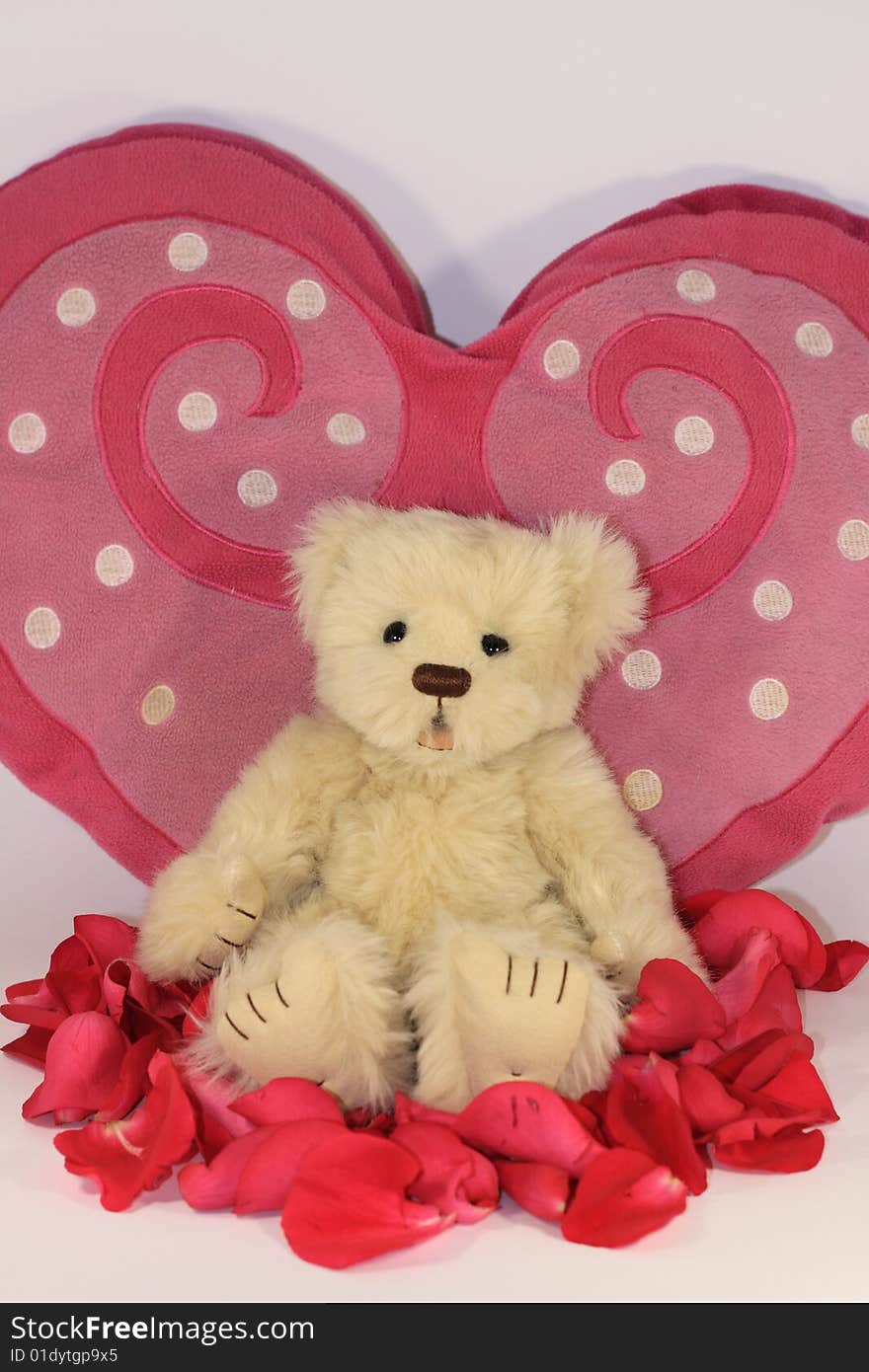 Teddy bear close to a heart with rose petals. Teddy bear close to a heart with rose petals