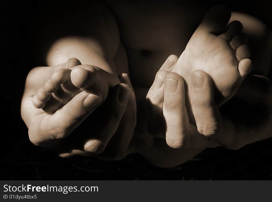 Dads hands with baby feet in sepia tone